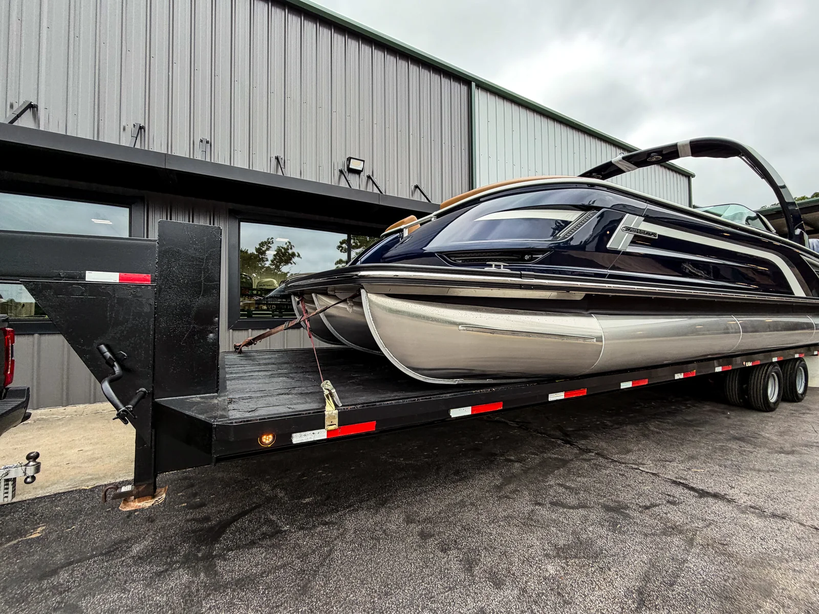 Tritoon strapped down on the Xclusive Transport gooseneck lowboy trailer ready for an oversize haul