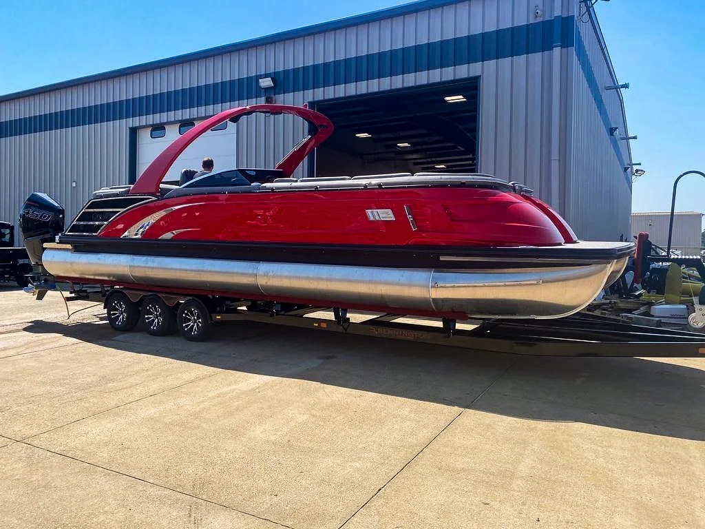 Red Bennington tritoon on its trailer outside a dealership, waiting to be collected for transport