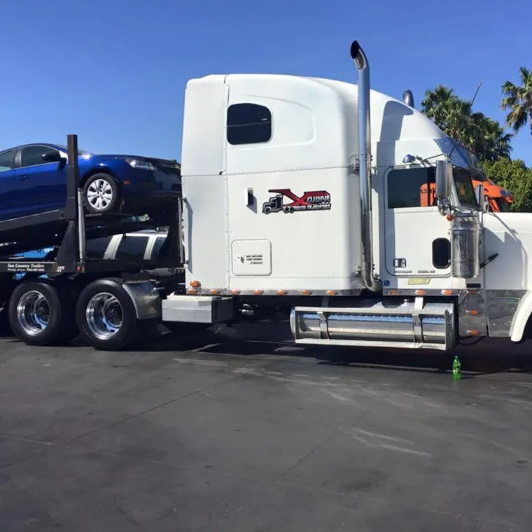 Customer car loaded on the Xclusive Transport open carrier under palm trees at the southern end of a run